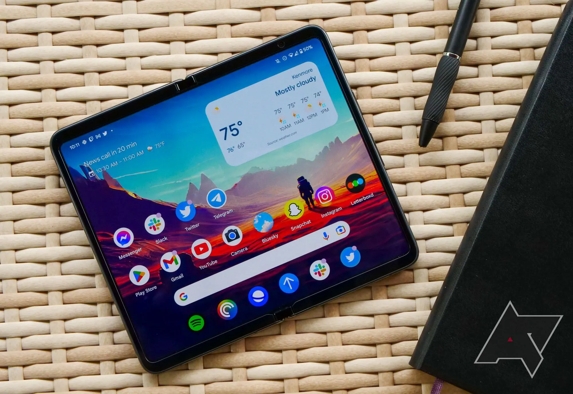 Điện thoại Google Pixel Fold đặt trên bàn mây cùng sổ ghi chép
