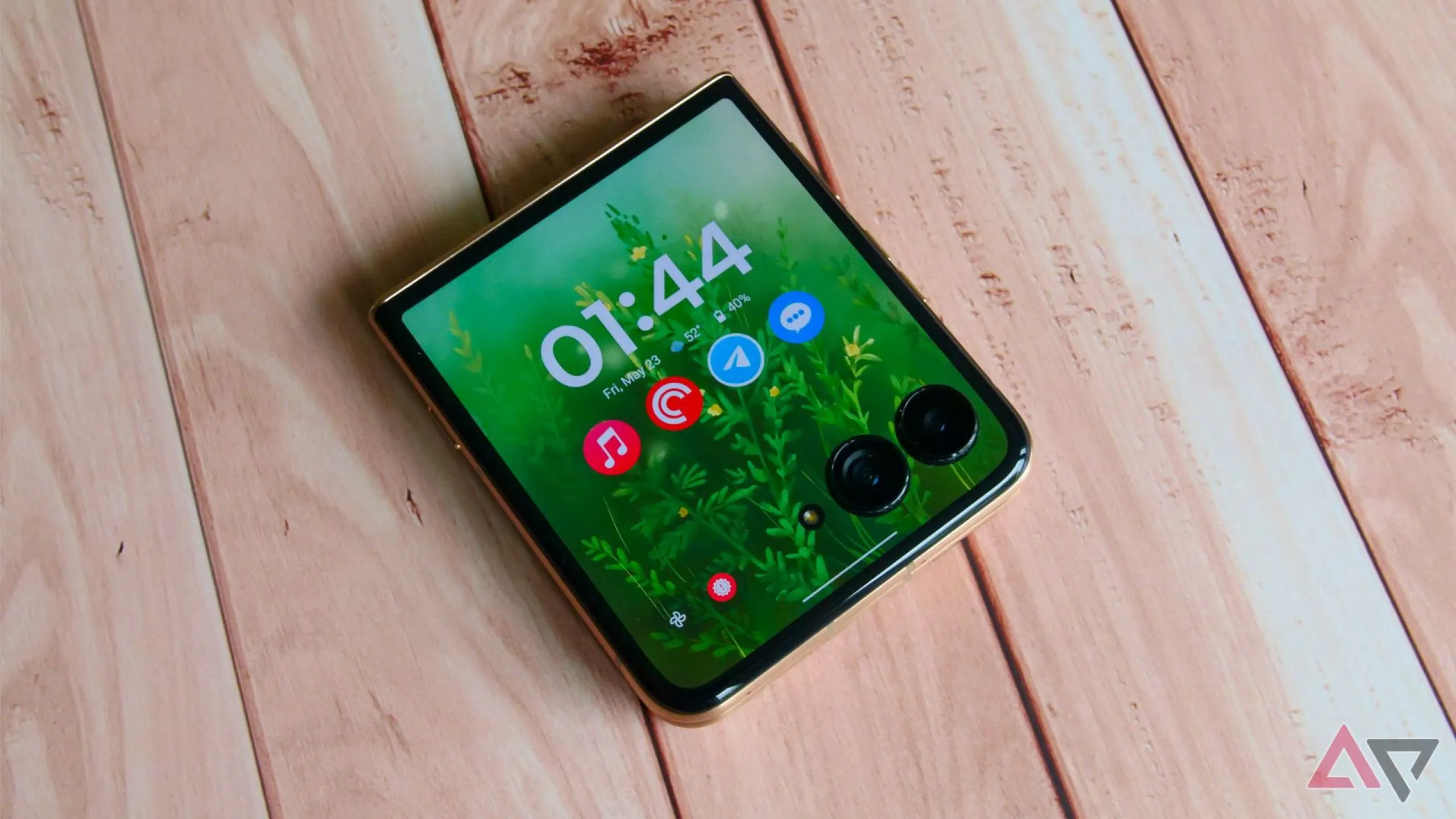 Điện thoại Motorola Razr Ultra 2025 màu xanh lá đặt trên bàn gỗ