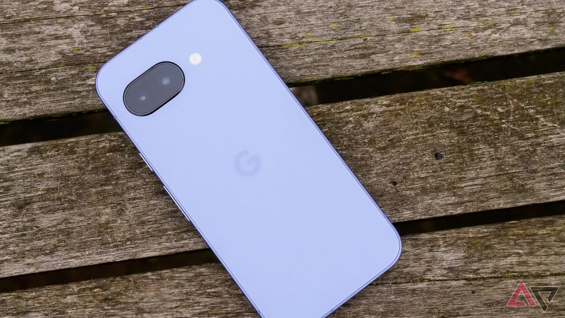 Google Pixel 9a đặt úp trên ghế gỗ ở công viên, thể hiện thiết kế mới