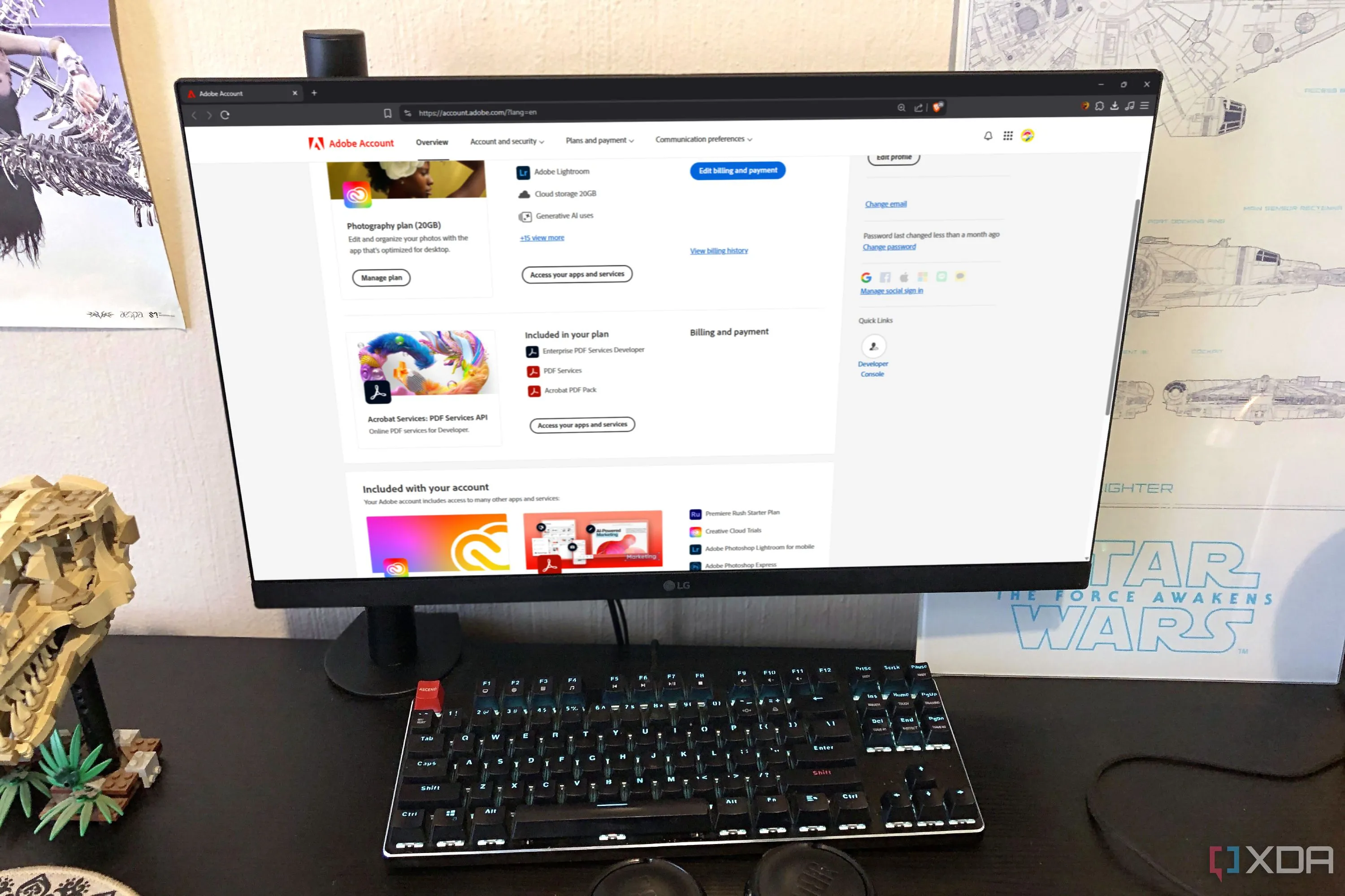 Giao diện website Adobe hiển thị trên màn hình máy tính bàn, kèm theo tai nghe, áp phích và đồ chơi Lego