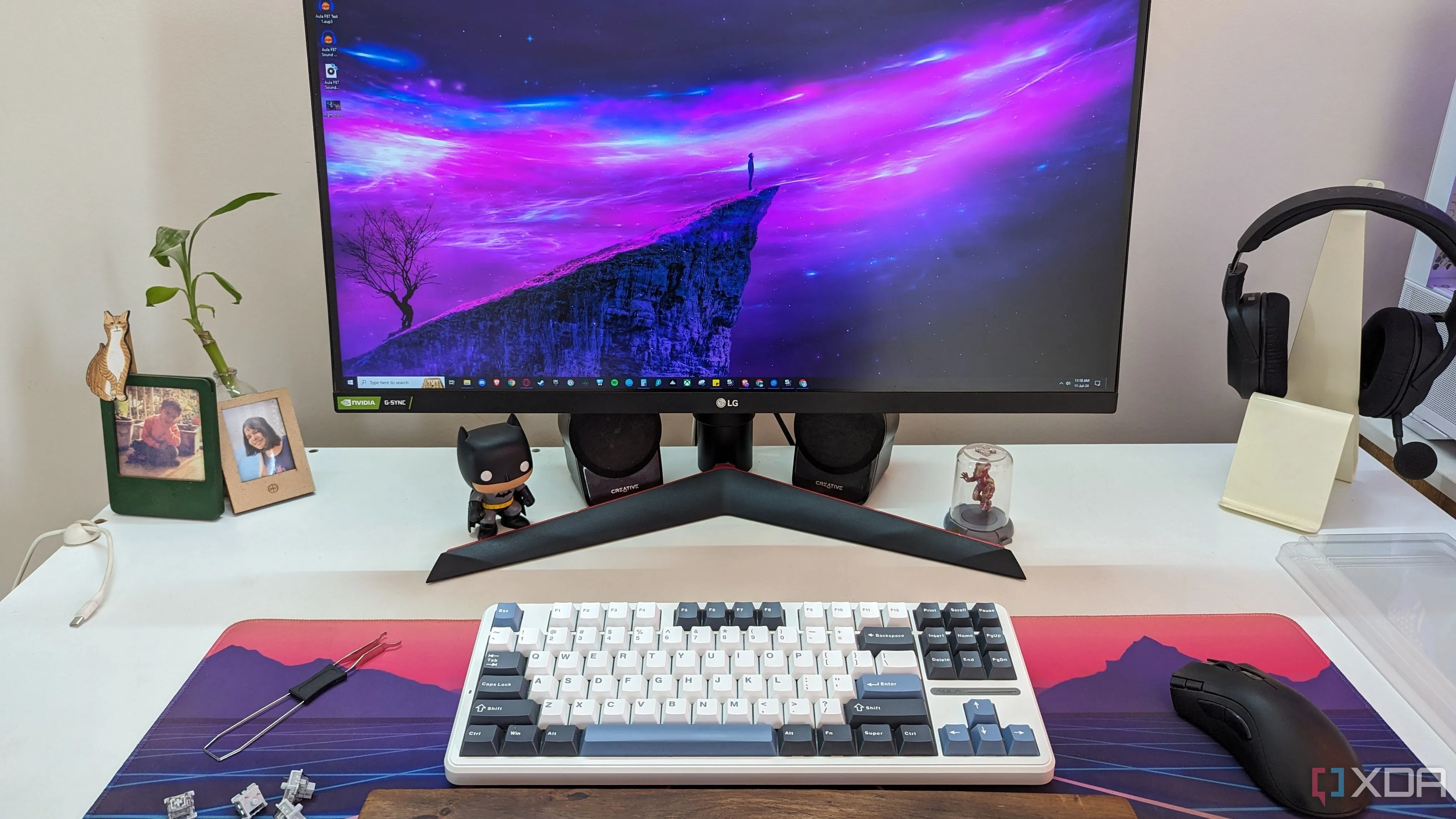 A mechanical keybaoard with a mouse on a deskmat next to a monitor
