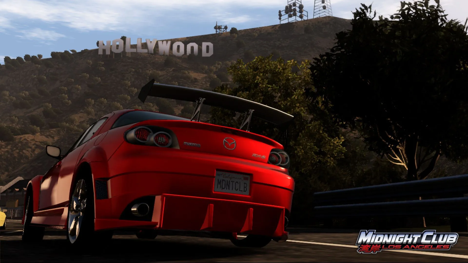 Ảnh chụp màn hình game Midnight Club: Los Angeles với xe Mazda màu cam và biểu tượng Hollywood