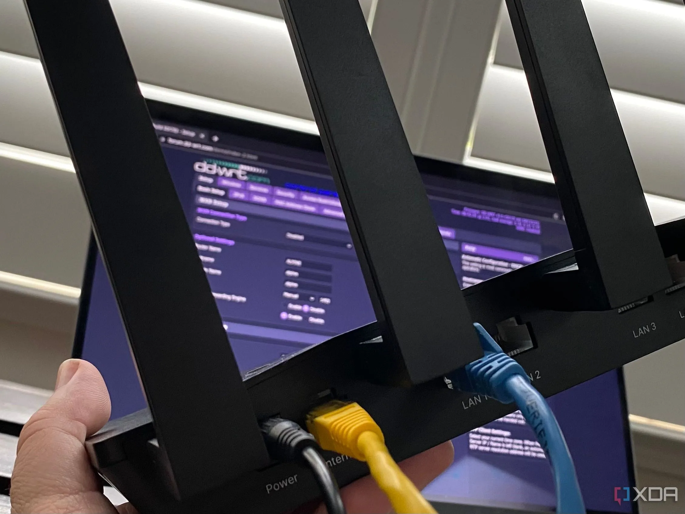 Bộ định tuyến Wi-Fi và laptop hiển thị phần mềm DD-WRT, minh họa kết nối mạng không dây