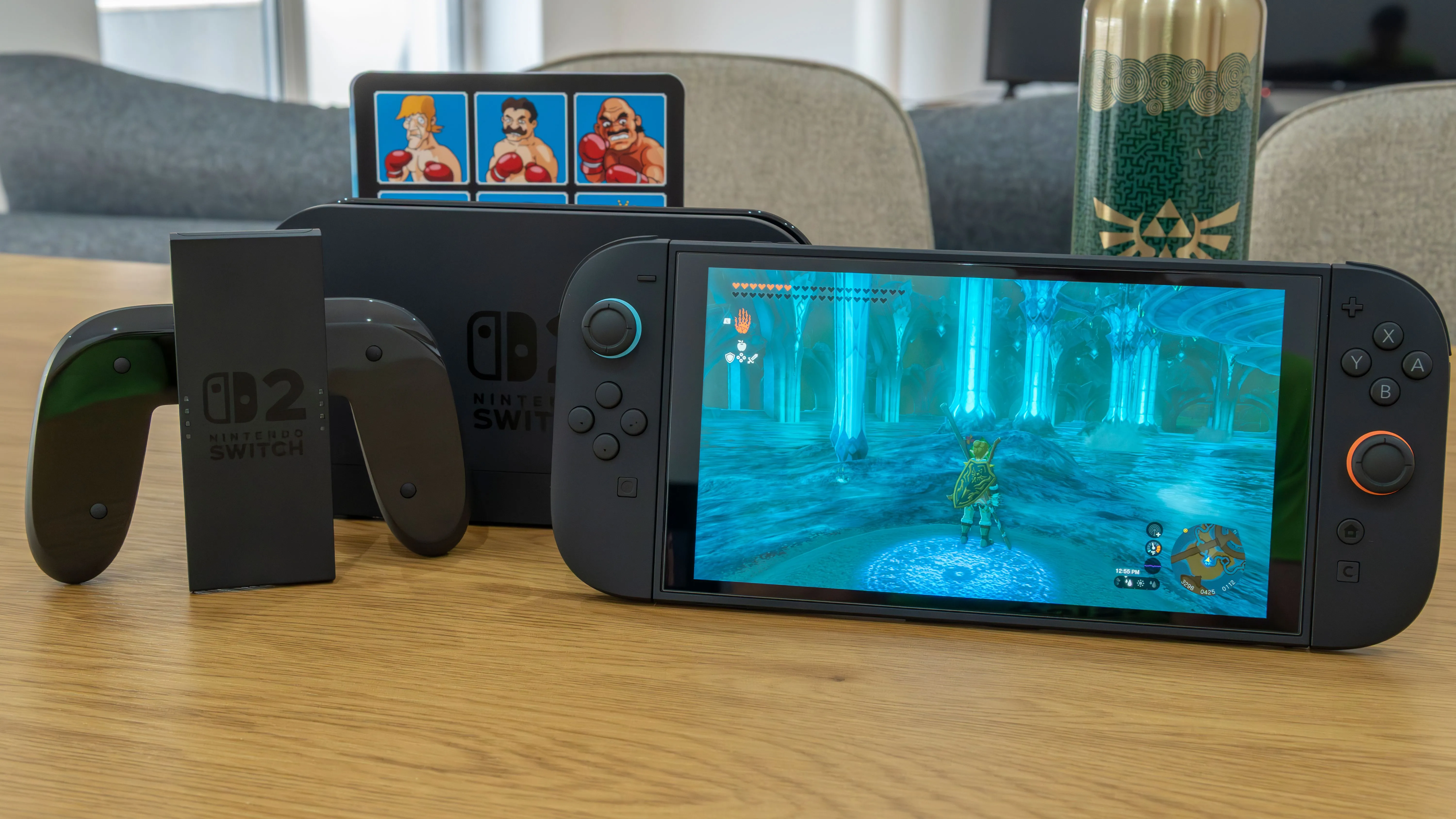 Console Nintendo Switch 2 với dock và tay cầm Joy-Con 2 trên bàn gỗ, màn hình hiển thị game The Legend of Zelda Tears of the Kingdom