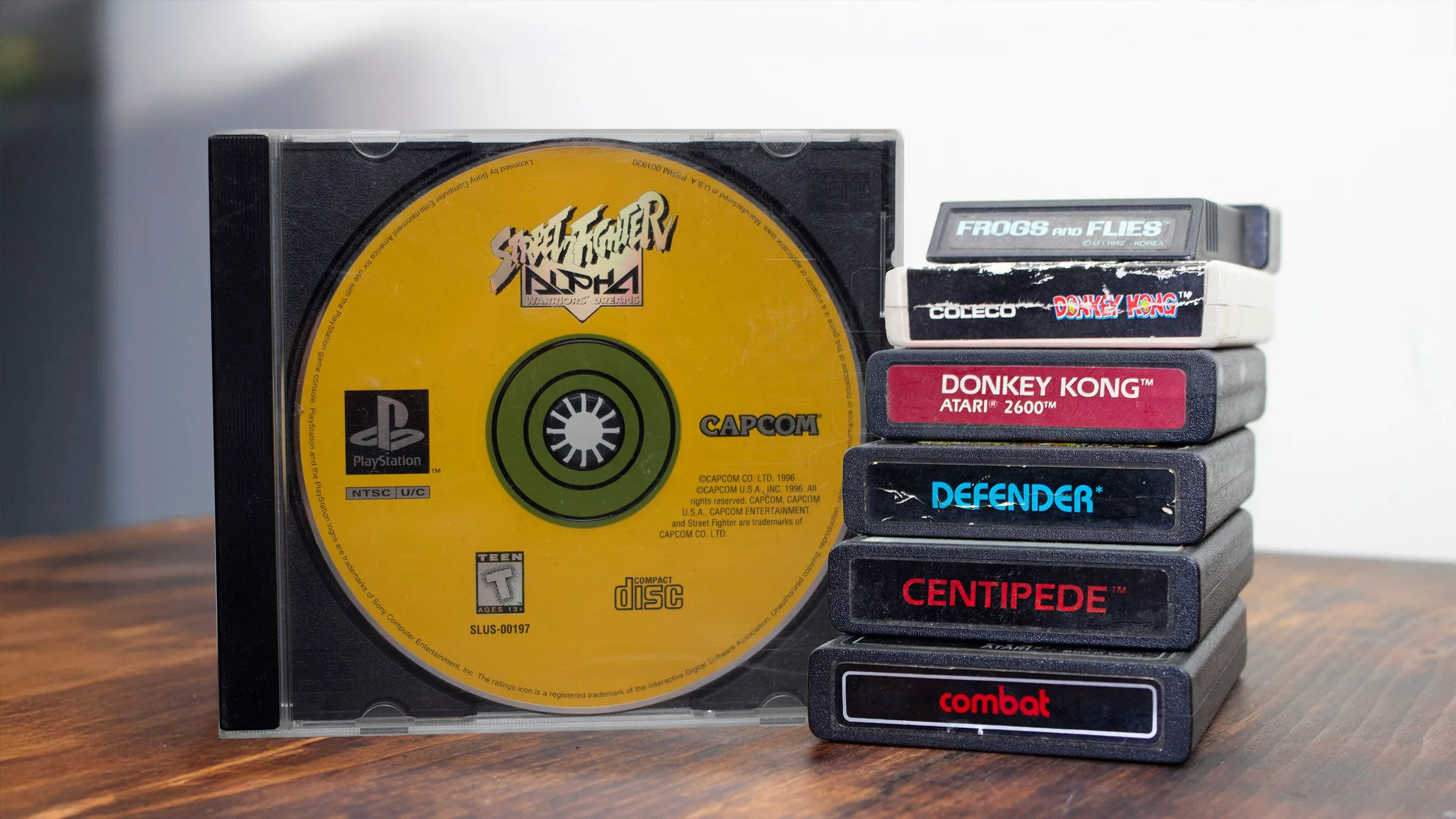 Đĩa game PS1 bên cạnh chồng game Atari và Coleco
