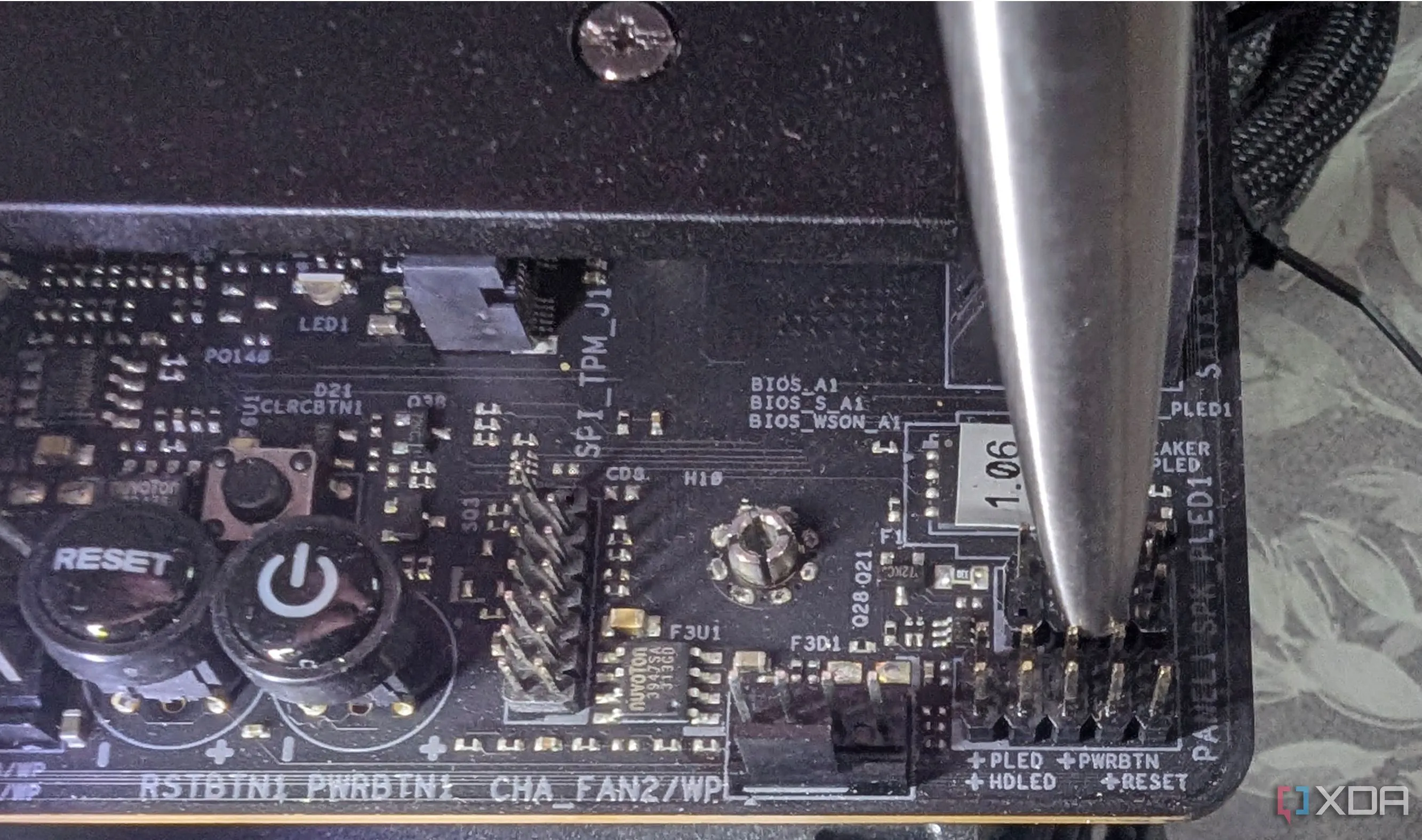 Dùng một vật kim loại như đầu bút chạm nhẹ vào hai chân PWRBTN và GND trên mainboard để kích hoạt quá trình khởi động, minh họa bước cuối cùng của việc kích nguồn nhanh PC.