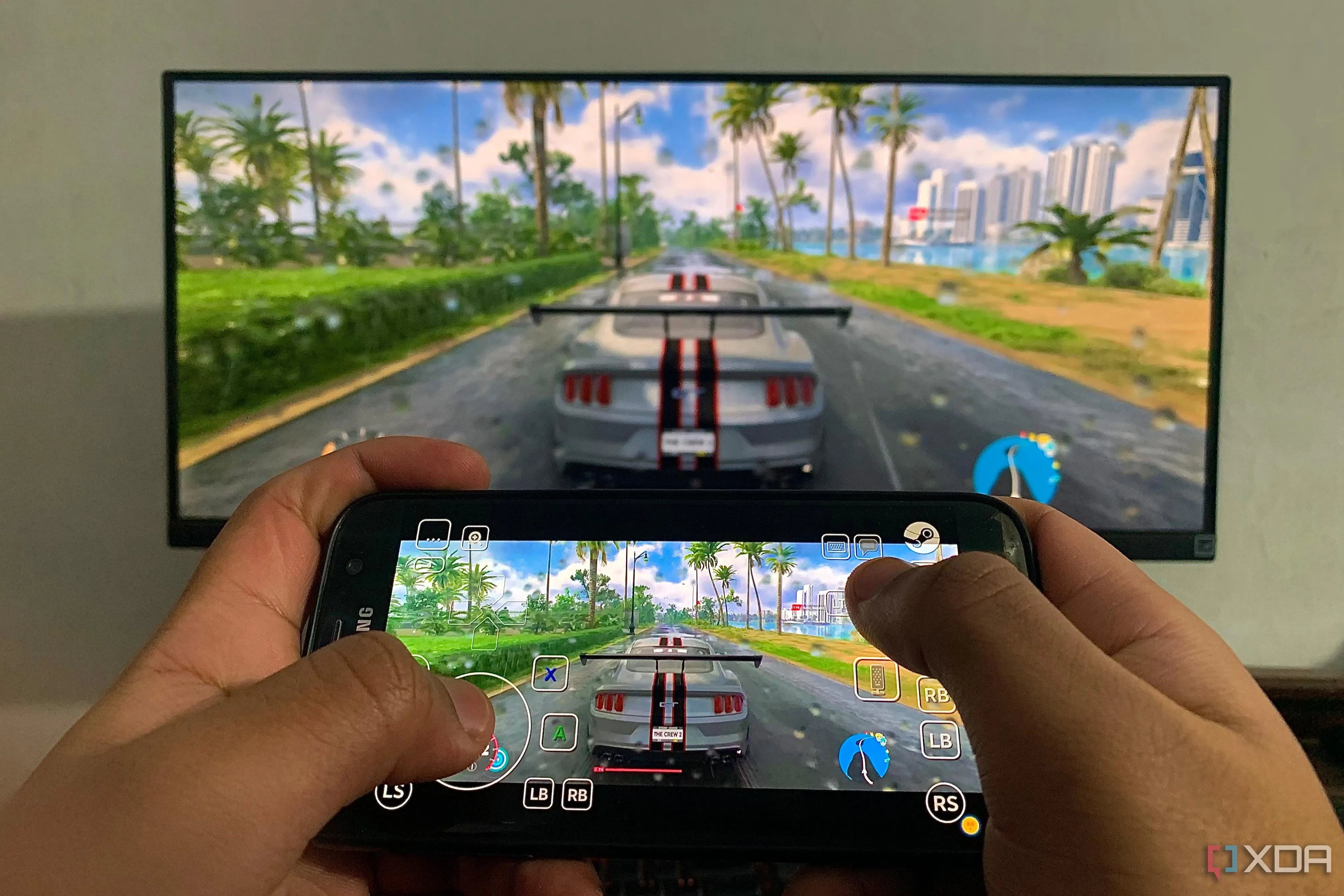 Hình ảnh chơi game The Crew 2 trên PC và truyền trực tiếp sang smartphone bằng Steam Link, minh họa tính năng remote play.