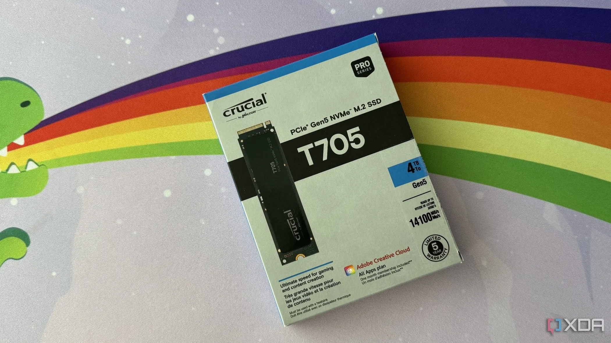 Hộp SSD Crucial T705 đặt trên thảm bàn gaming cầu vồng, minh họa một sản phẩm SSD PCIe 5.0 cao cấp