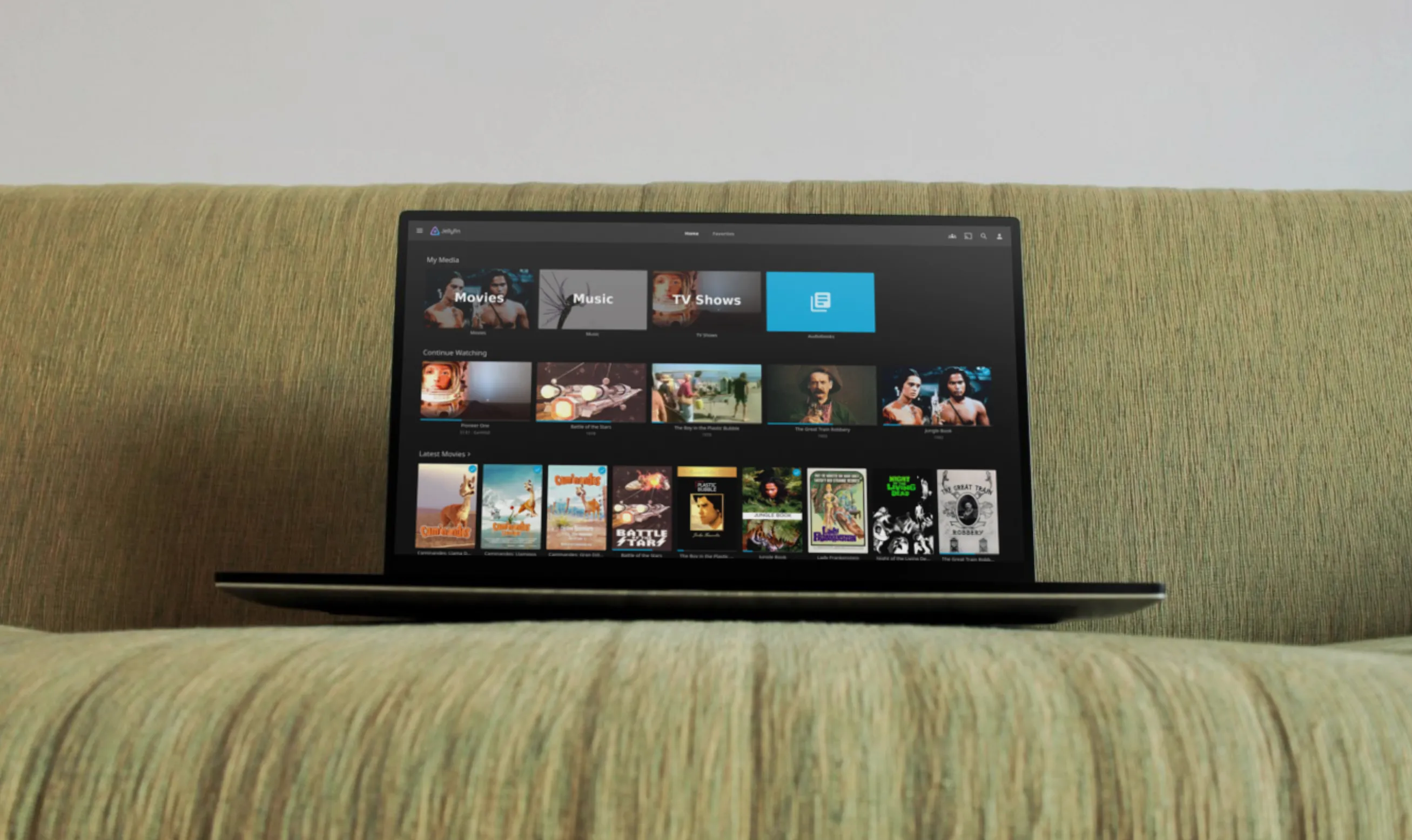 Laptop trên ghế sofa hiển thị giao diện Jellyfin, minh họa trải nghiệm nghe nhạc tại nhà