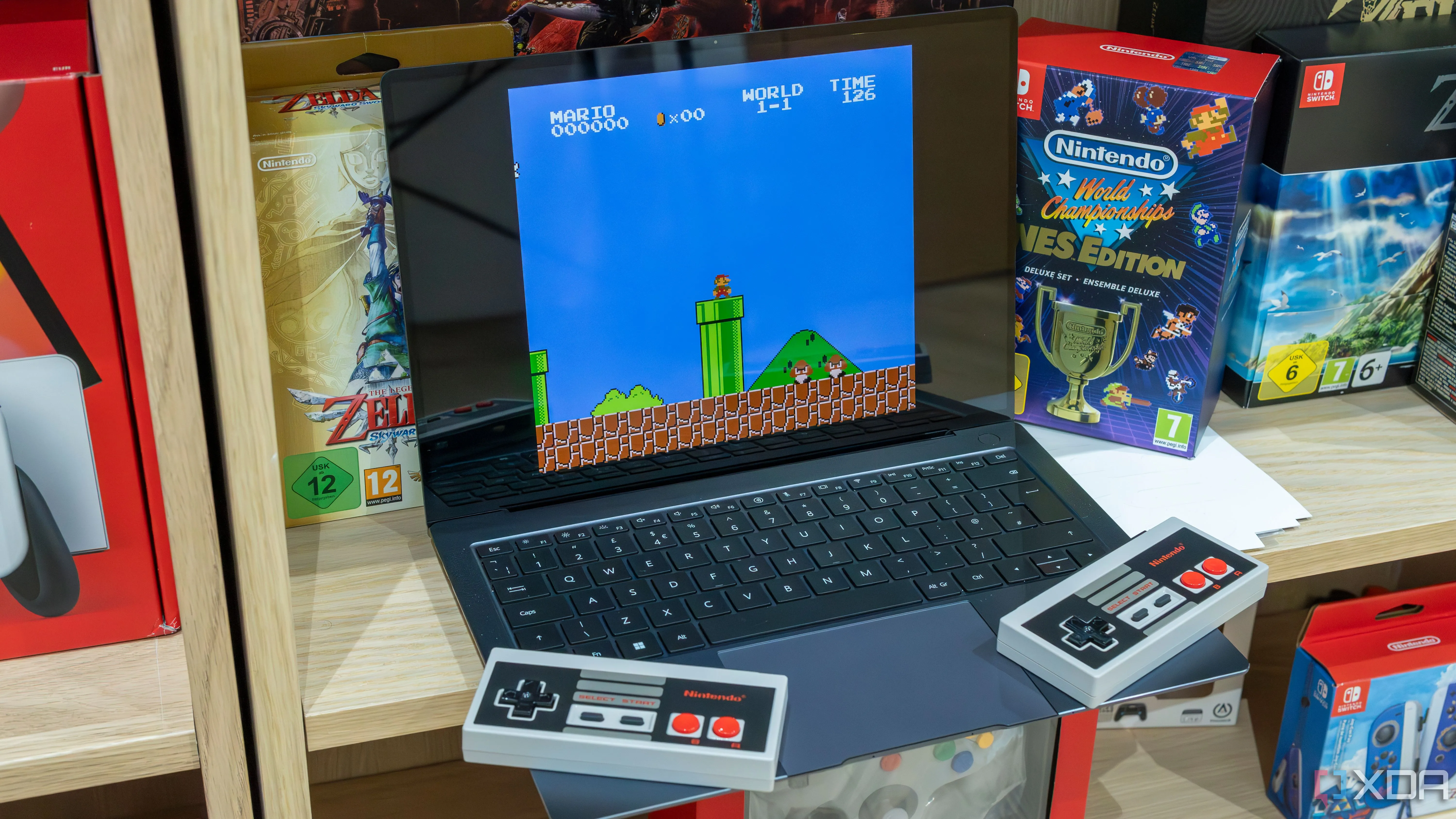 Laptop Windows 11 chạy giả lập game Super Mario Bros cổ điển với hai tay cầm NES không dây.