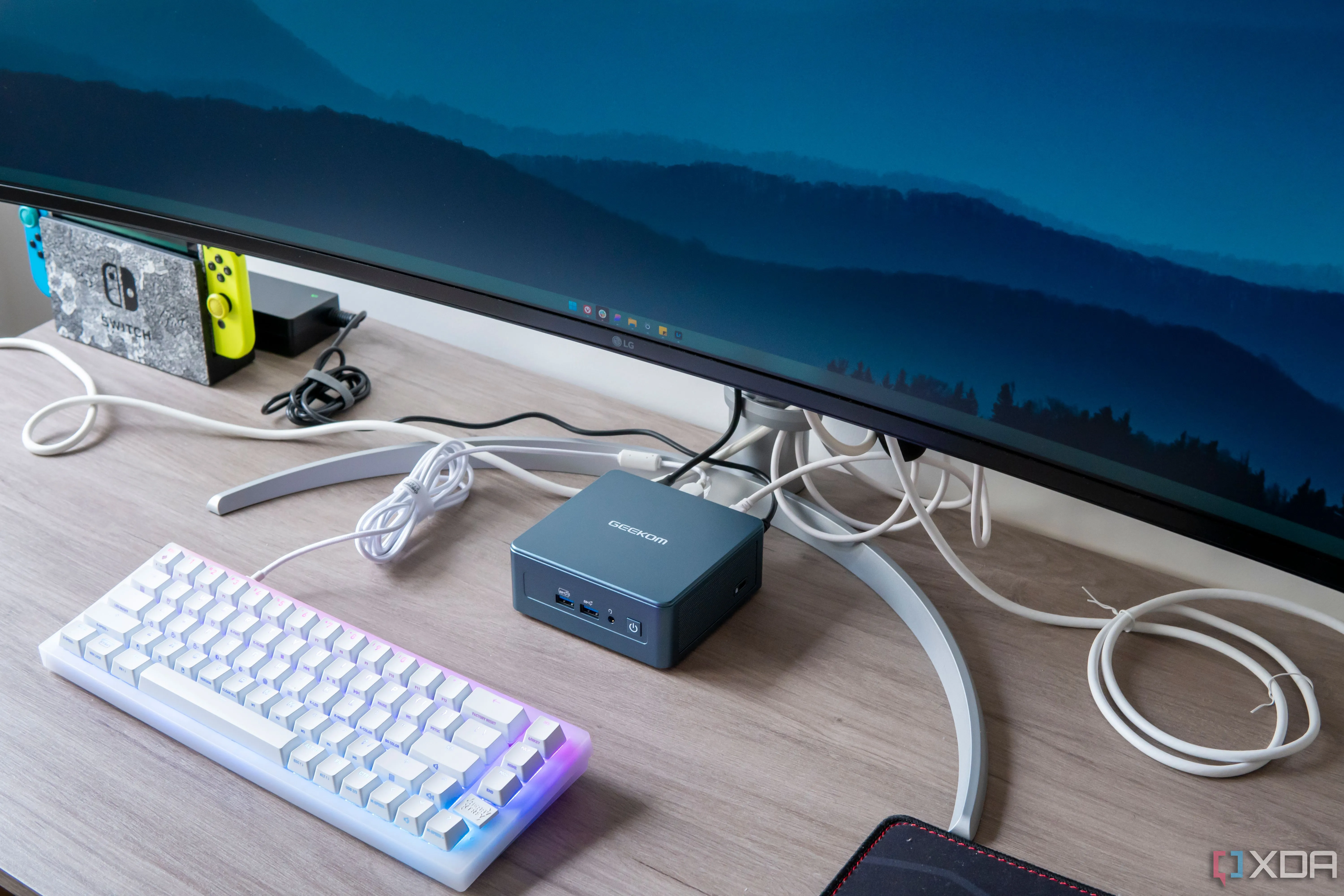 Máy tính mini Geekom Mini IT13 với màn hình và bàn phím, minh họa hệ thống chạy Windows 11 và thanh tác vụ