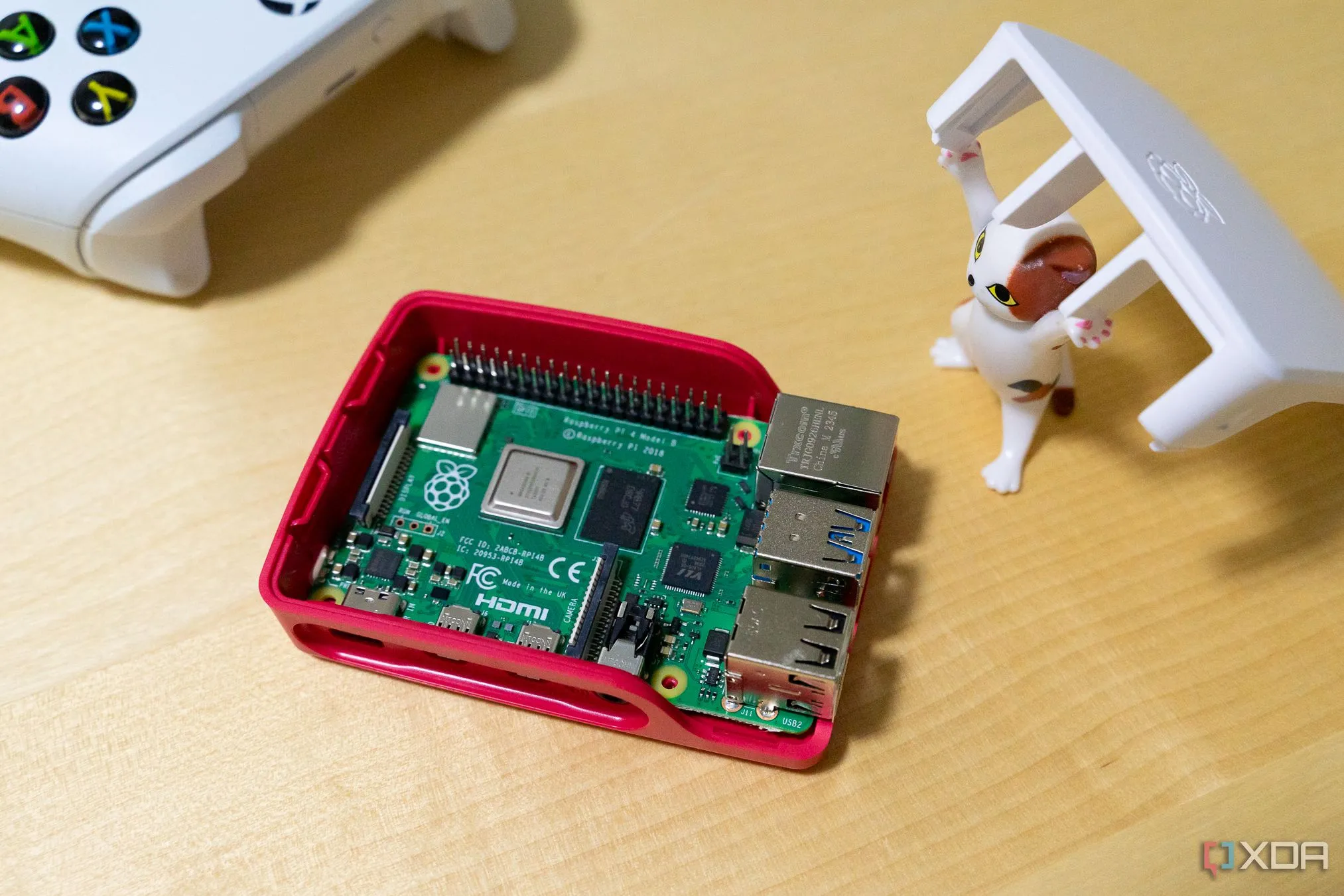 Một chú mèo đồ chơi đang nâng nắp hộp cho thấy bo mạch Raspberry Pi bên trong, minh họa khả năng chạy Homarr trên phần cứng nhỏ gọn