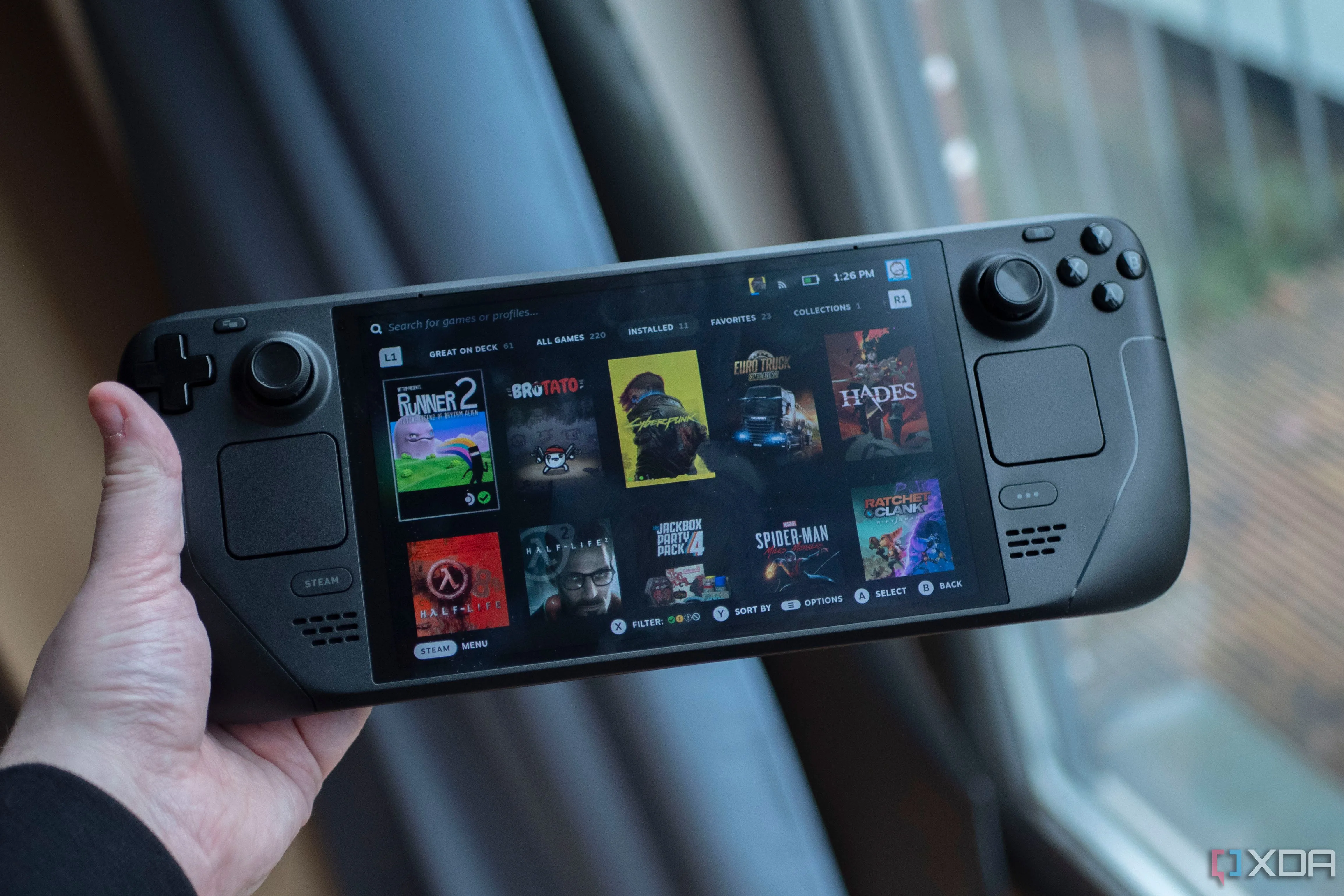 Một người chơi đang cầm Steam Deck OLED với màn hình hiển thị game, thể hiện trải nghiệm chơi game trên nền tảng di động của Steam.