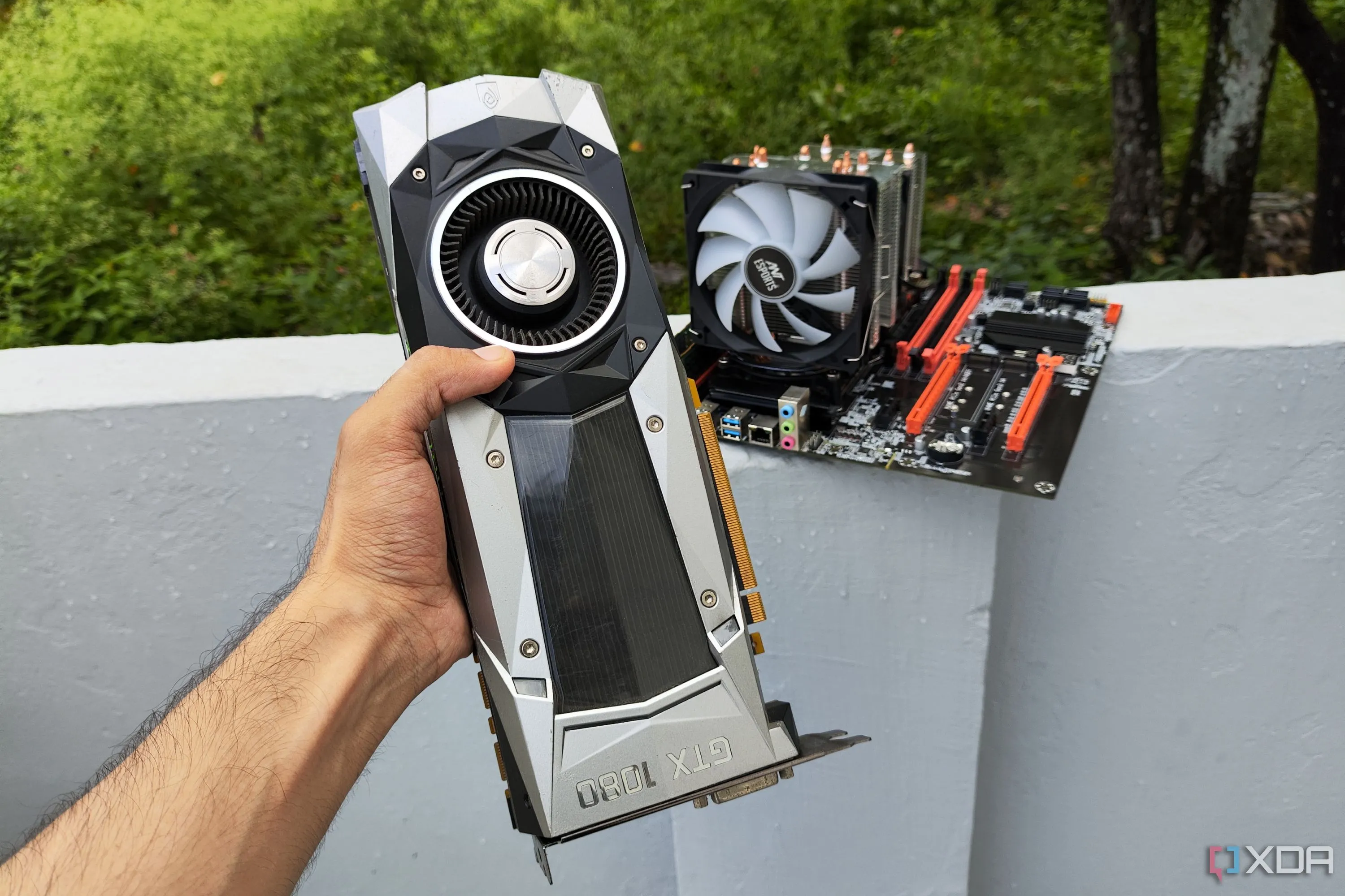 Người đang cầm card đồ họa GTX 1080 Founders Edition trước một máy tính server, tượng trưng cho việc kết hợp linh kiện cũ và mới để xây dựng PC gaming giá rẻ với CPU Xeon
