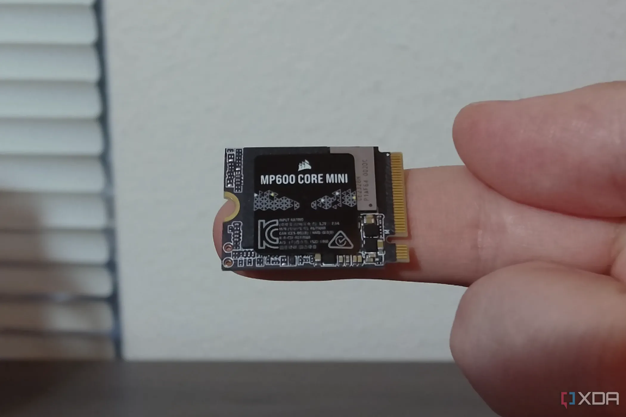 Ổ cứng SSD Corsair MP600 Core Mini M.2 NVMe đang được giữ trên ngón tay, minh họa kích thước và M keying của SSD M.2
