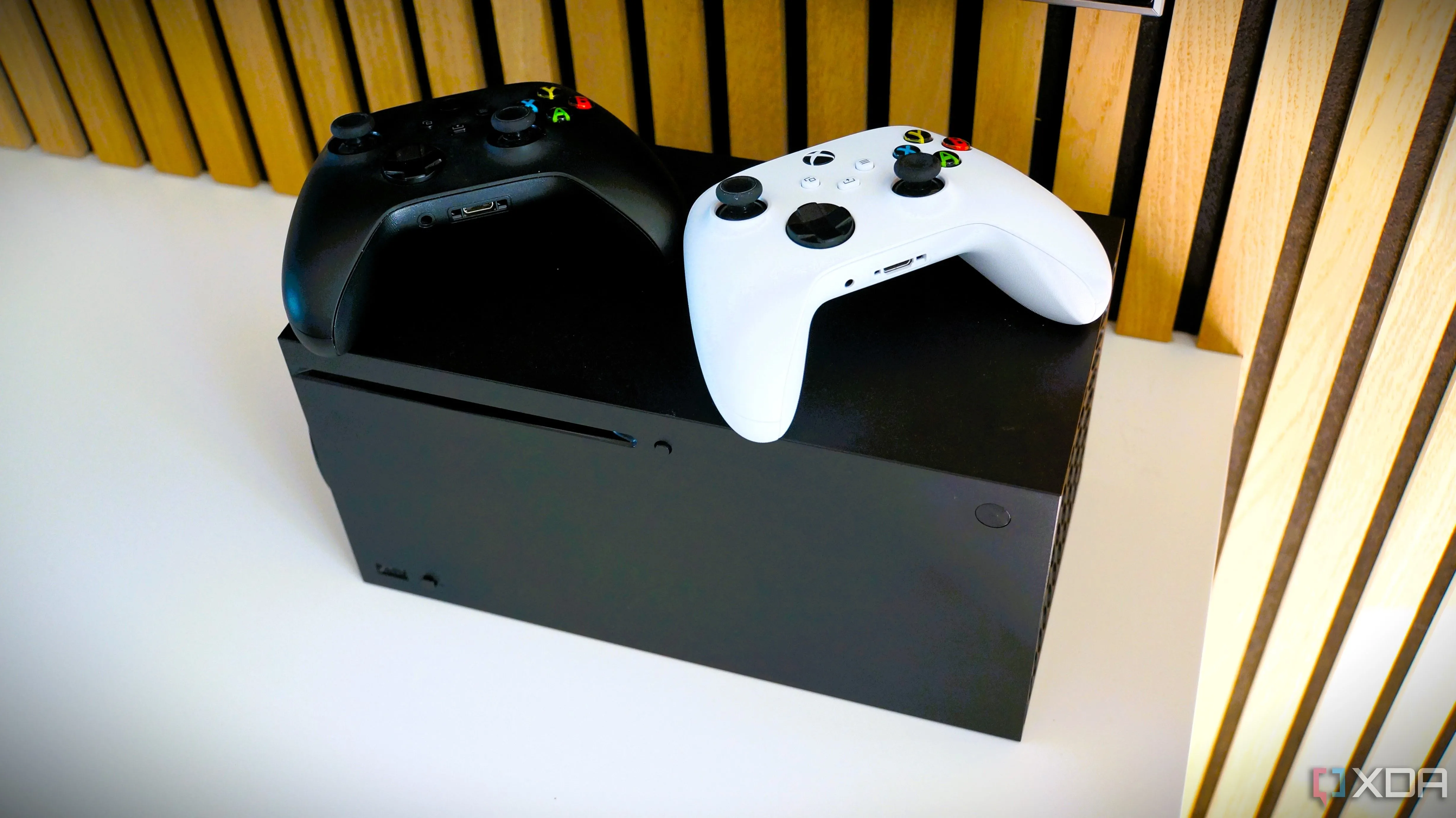 Xbox Series X với tay cầm đen và trắng đặt phía trên